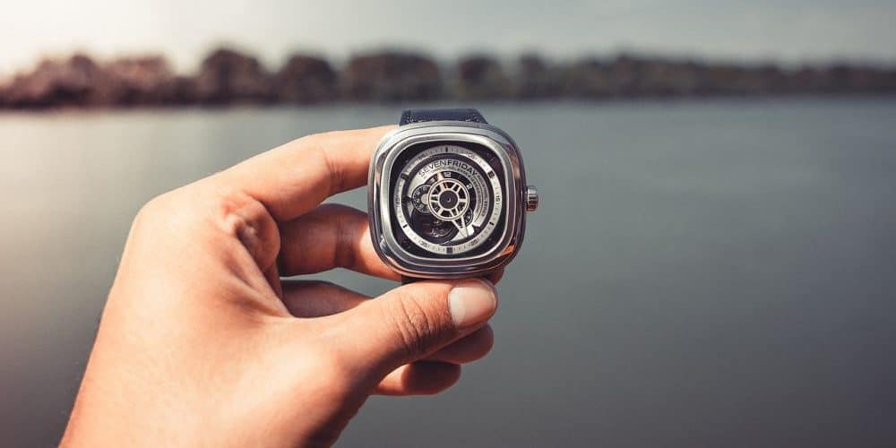 a watch being held with a lake background
